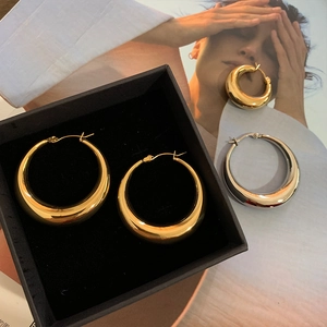 Macro shot of thick gold and silver polished hoop earrings on a fashion magazine