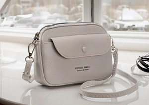Close-up of grey litchi texture leather crossbody bag with front flap and snap button