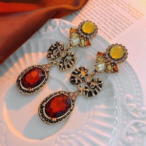 Detail of vintage baroque earrings with deep red oval gemstones and antique bronze finish
