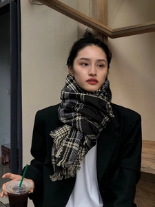 Détail d'une écharpe à carreaux noir et beige avec franges sur un mannequin élégant