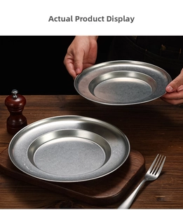 Detailed close-up of matte silver stainless steel pasta plate with wide rim on wooden table