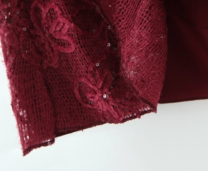 Detail of burgundy lace fabric with intricate mesh embroidery and shiny sequins