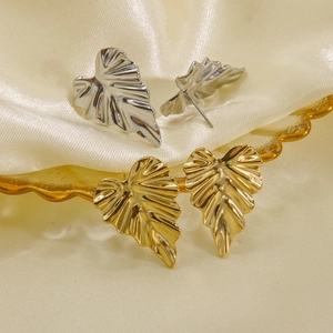 Elegant gold and silver leaf earrings in titanium steel on silk fabric display