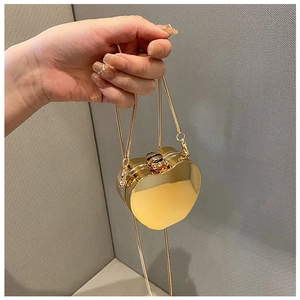 Close-up of heart-shaped gold mirror finish mini bag with metallic snake chain strap