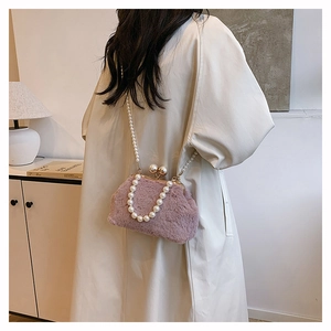 Detailed view of a pink plush shell bag featuring elegant pearl straps and golden clasp