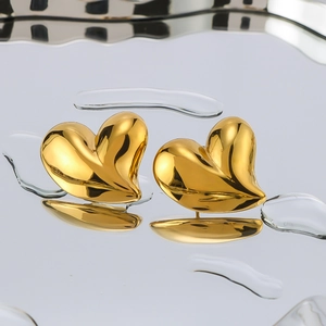 Stereo heart-shaped stainless steel earrings in 18K gold finish on a water reflection surface