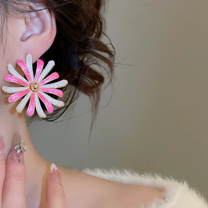 Dettaglio dell'orecchino a fiore in smalto rosa e bianco con centro dorato indossato