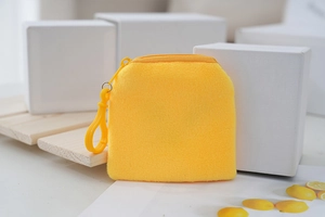 Detail view of the soft yellow plush toast coin purse with a zipper and plastic hook