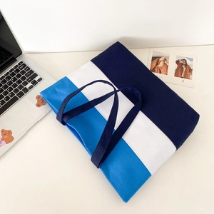 Detailed flat lay of a tricolor navy and blue canvas tote bag on a minimalist desk