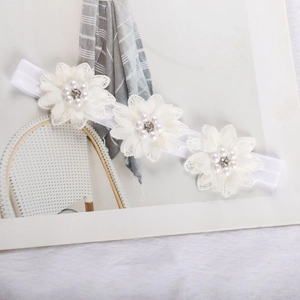 Detailed view of three white chiffon flowers with pearls on elastic baby headband