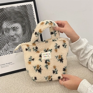 Nahaufnahme einer flauschigen Sherpa-Tragetasche mit Blumenmuster und Webetikett