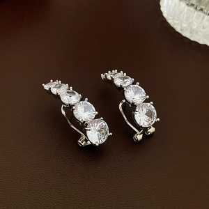 Vue macro de boucles d'oreilles géométriques argentées serties de zircons étincelants