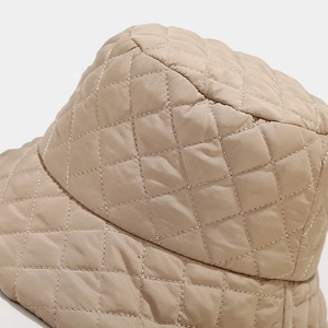 Close-up of beige quilted bucket hat with diamond stitching and metallic thread details