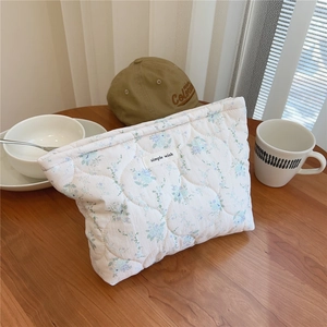 Detailed shot of floral quilted cotton makeup bag with simple wish label on wood table