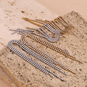 Close-up of dangling zircon tassel earrings in gold and silver finish with stone texture