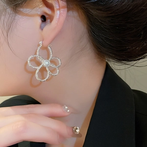 Silver flower earrings with pearl accent worn by model showing elegant floral design