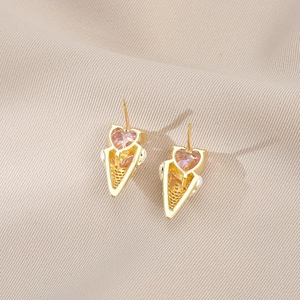 Boucles d'oreilles cornet de glace cœur dorées avec zircon rose sur tissu beige