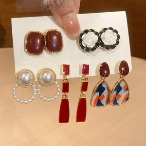 Detail view of five assorted elegant earring sets featuring pearls and floral oil drip designs