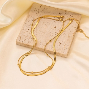 Minimalist gold-plated double-layer snake and bead chain necklace on stone background