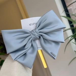 Elegant grey-blue satin bow hair clip with silver metal lettering on white card