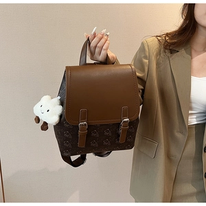 Détail d'un sac à dos marron en similicuir avec motifs ours et breloque nuage