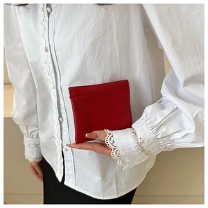 Close-up of a deep red matte leather mini coin purse with squeeze opening design