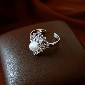 Detailed close-up of a silver floral ring with a central pearl and zircon accents