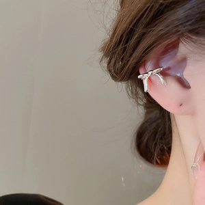 Detailed view of silver bow-shaped ear cuff with pearls and zircon on model ear