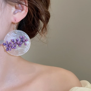 Detailed side view of elegant asymmetrical purple flower tassel earrings worn by a model