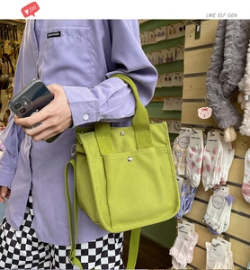 Side view of lime green canvas tote bag with adjustable strap and metal rivet details