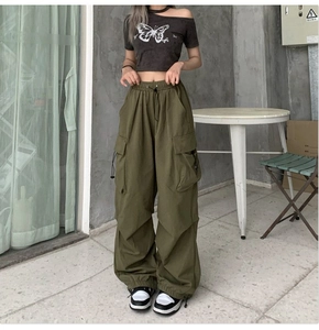 Detail of olive green cargo pants featuring drawstring waist and large side flap pockets