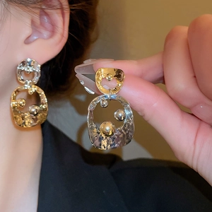 Macro shot of bicolour gold and silver tassel earrings with hammer-textured metal finish