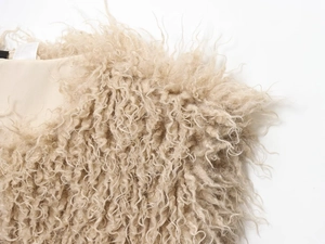 Macro shot of fluffy beige curly faux fur texture highlighting plush soft material detail