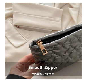 Close-up of smooth metal zipper on grey quilted heart pattern cosmetic organizer bag