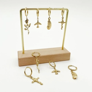 Golden huggie earrings set featuring rose, airplane, feather, and cross pendants