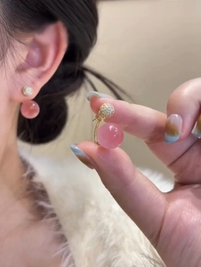 Detailed view of sweet pink flower earrings with golden crystals on ear lobe