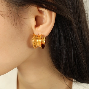 Vintage golden stainless steel C-shaped earrings with wave texture on model