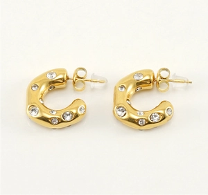 Macro view of gold-plated C-shape earrings featuring crystal-inlaid irregular metal band