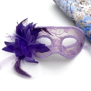 Détail d'un masque de bal masqué en dentelle violette avec plumes et paillettes