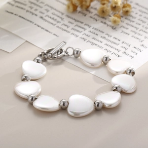 Détail d'un bracelet cœur en nacre avec perles dorées et fermoir OT sur papier rétro