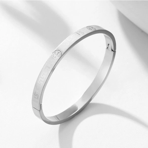 Detail of silver stainless steel cuff bracelet with JESUS IS text and religious icons