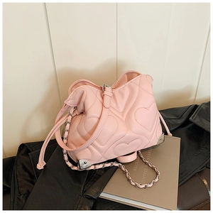 Detail of heart-quilted pink bag with silver chain strap and metal corner accents