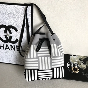 Close-up of woven bucket bag with houndstooth pattern and black drawstring closure
