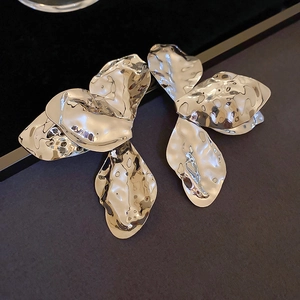 Macro shot of silver twisted hoop earrings with polished petal design and metallic shine