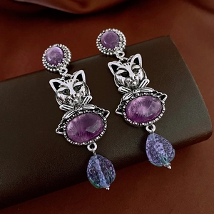 Detailed close-up of vintage cat earrings with purple stones and silver drop pendants