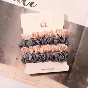 Detail view of four-piece satin scrunchies set in pink and grey on display card