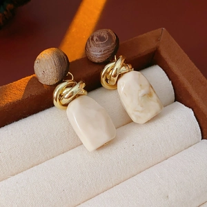 Close-up of vintage wood and resin geometric earrings on a jewelry box display