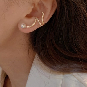 Elegant gold pearl ear cuff with shimmering diamonds and wave curve design worn on ear