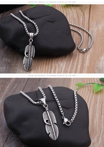 Détail d'un pendentif plume vintage en acier argenté avec sa chaîne à maillons fins