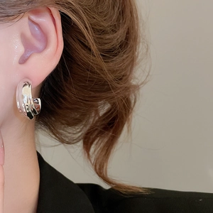 Polished chunky silver hoop earring worn by a model in a close-up lifestyle shot